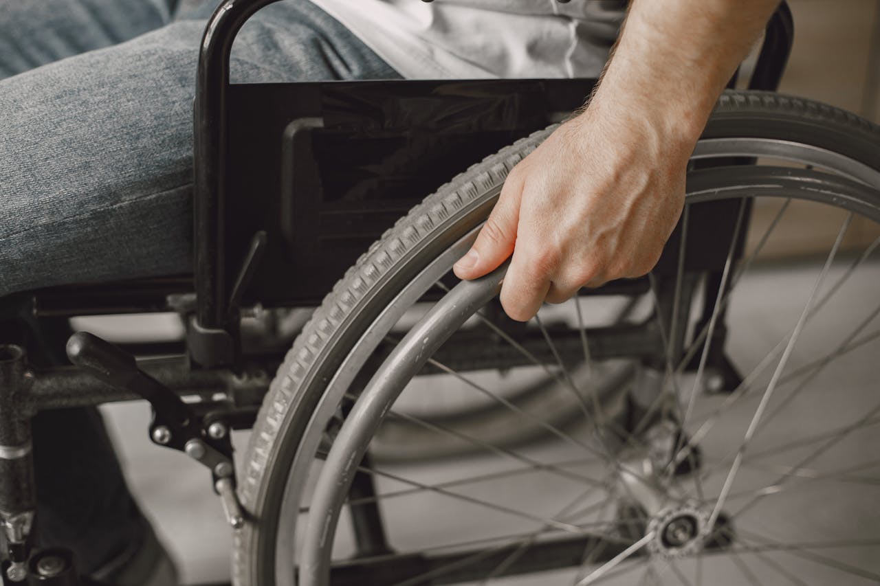 A close-up image showing a hand gripping a wheelchair wheel, portraying mobility and accessibility.