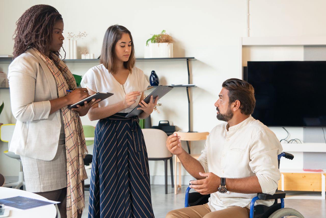 gallery-1 Three coworkers in a contemporary office having a discussion, fostering teamwork and inclusion.